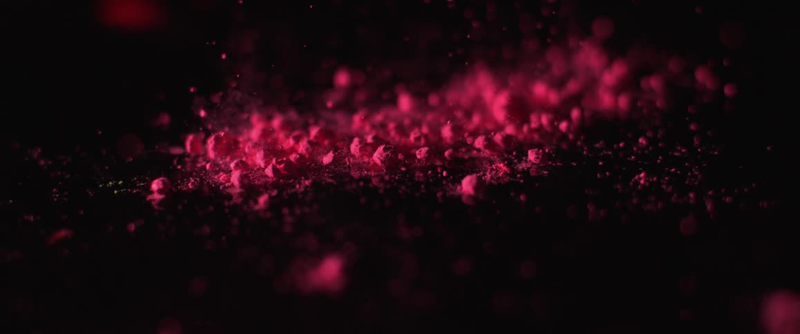 Pink powder vibrating into the air from a black surface