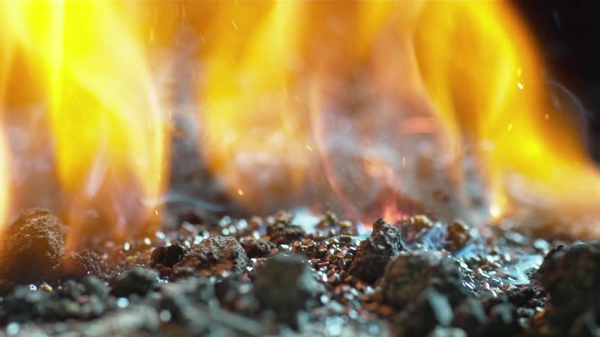 Smoke rises from hot embers and then they burst in to flames