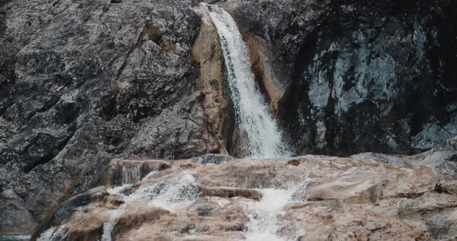 A waterfall flowing down cliffs and over rock to the river