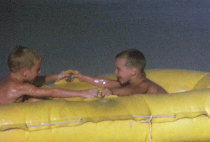 Two children are in a yellow raft playing in the water