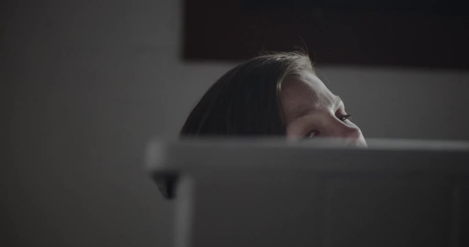 A young woman reclines in a bathtub as she pensively stares upwards