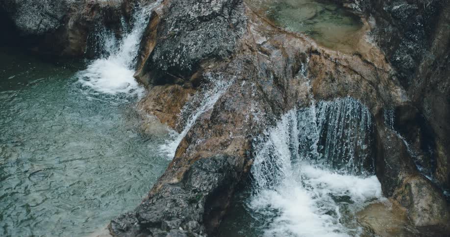 Water flows over the mountains into the lake below
