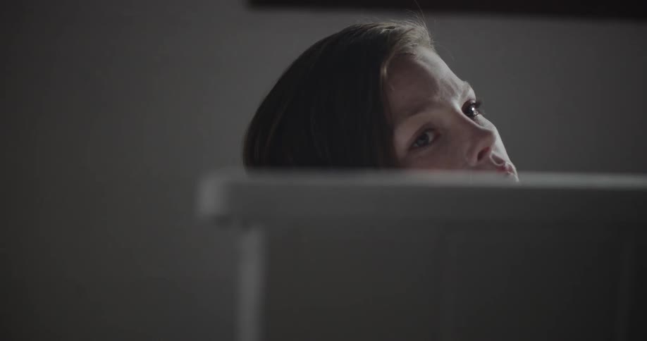 A young woman reclining in a bathtub pensively looks off into the distance