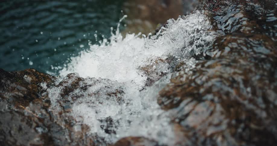 Close up of a waterfall flowing in slow motion down rocks into a pool in a canyon