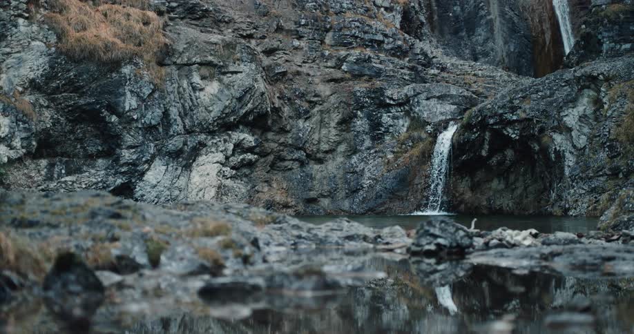 Landscape view of water running down the side of a cliff in to the pond below