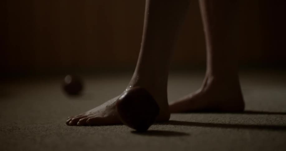 Apples rolling on the ground close to a woman feet