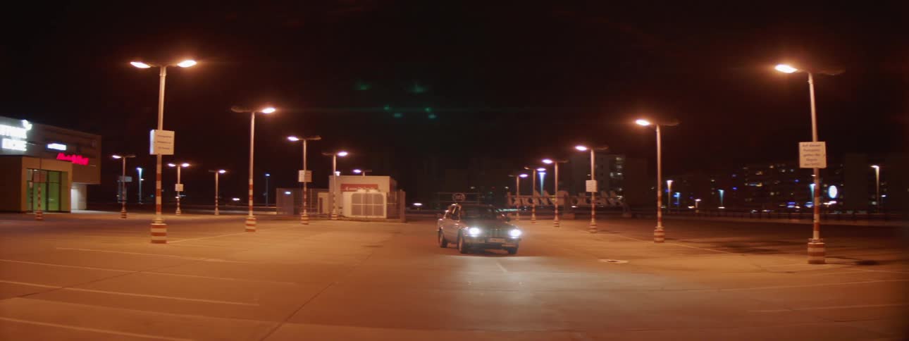 A car speeding through an empty parking lot at night