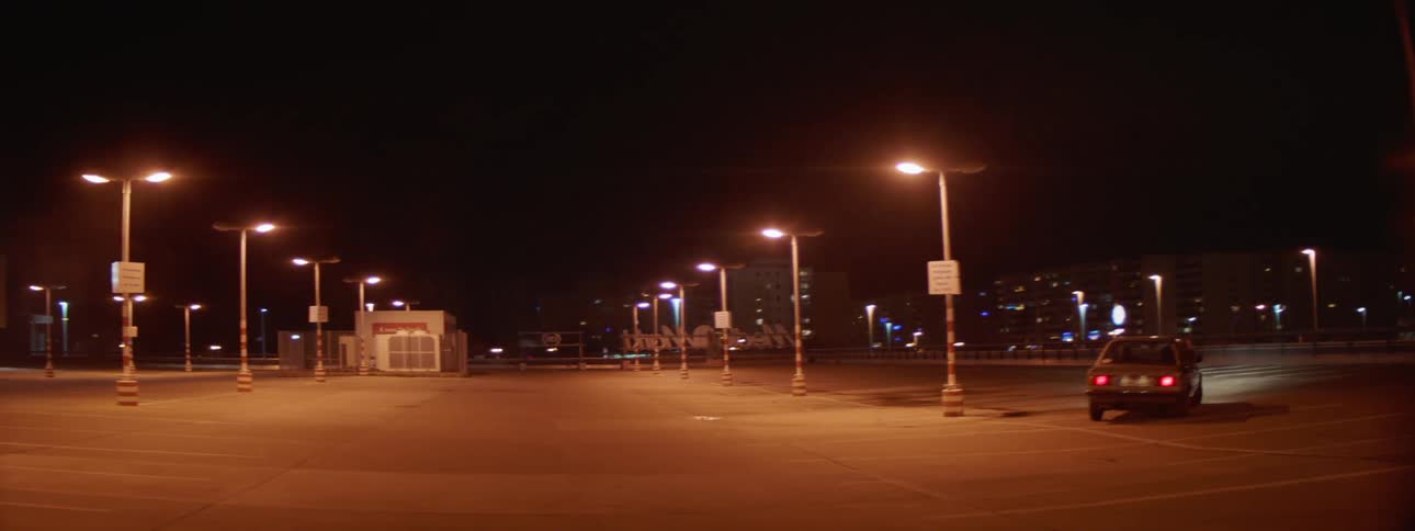 A car drives around poles in a parking lot