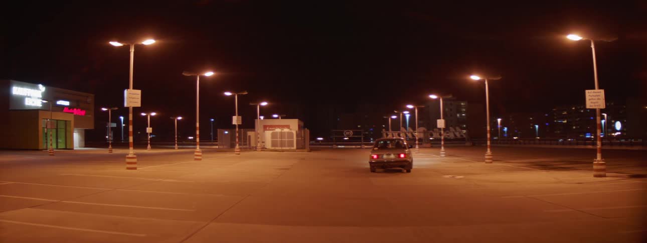 A car swerving through an empty parking lot at night
