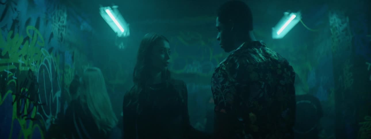 Couple enters a party in a nightclub with strobe lights and graffiti on the walls
