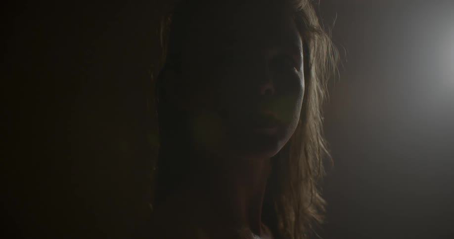 Close up of woman on a dim lit room turning her face to the camera