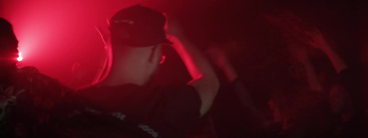 People dance in dark room under flashing lights