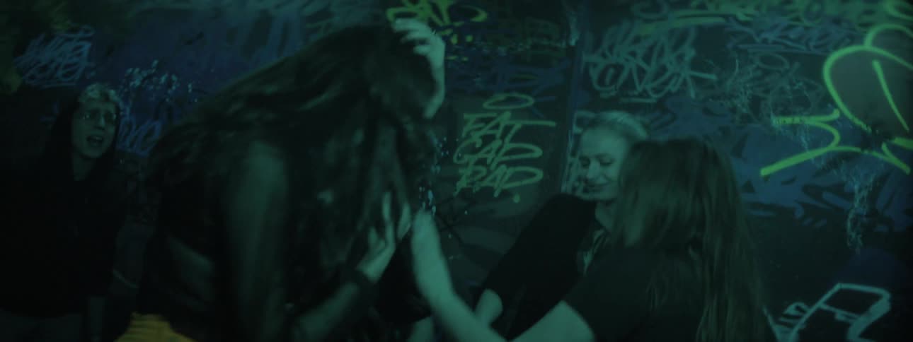 Men and women dance under a strobe light in a graffiti lined room