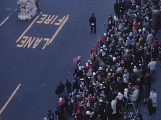 A parade is going down the street as crowds of people watch