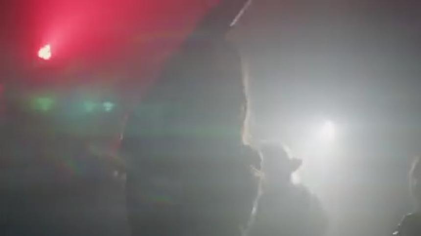 People dancing in a dark club as colored lights flash