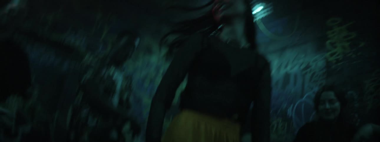 A group of teenagers dance in a room with flashing lights