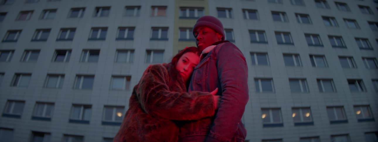 Couple standing in front of apartment building under red light