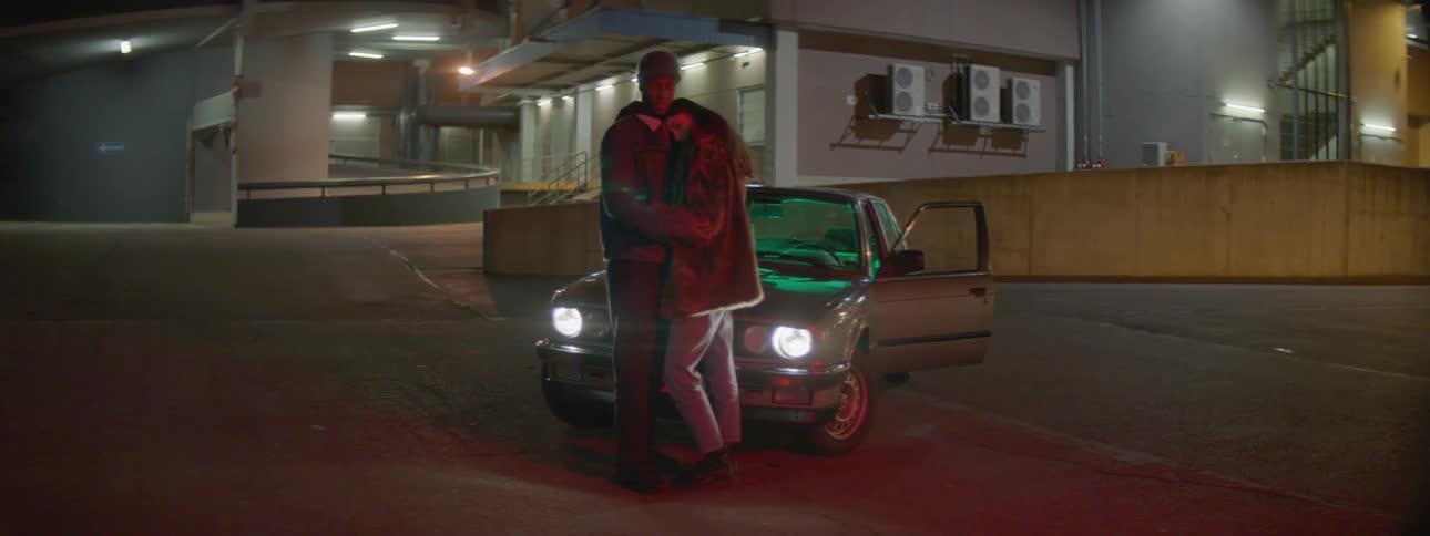 A man and a woman in front of a car hugging