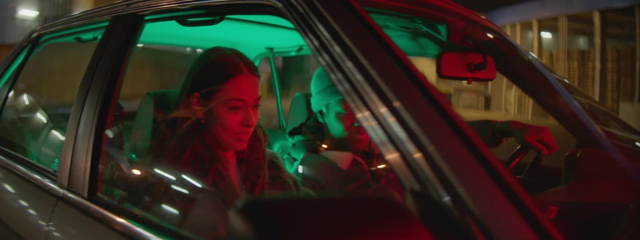 A man and woman sit in a car and talk
