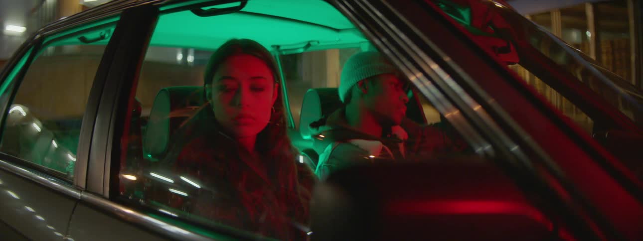 A man and woman sit in a stopped car