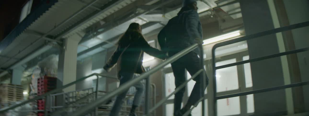 A man and woman jog up some stairs and down a walkway by a building