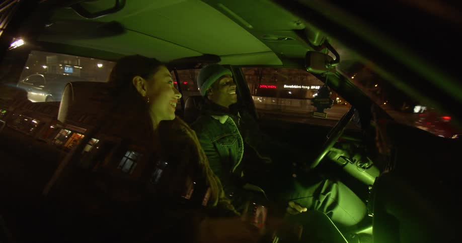 A man and woman talk and laugh while driving in the car