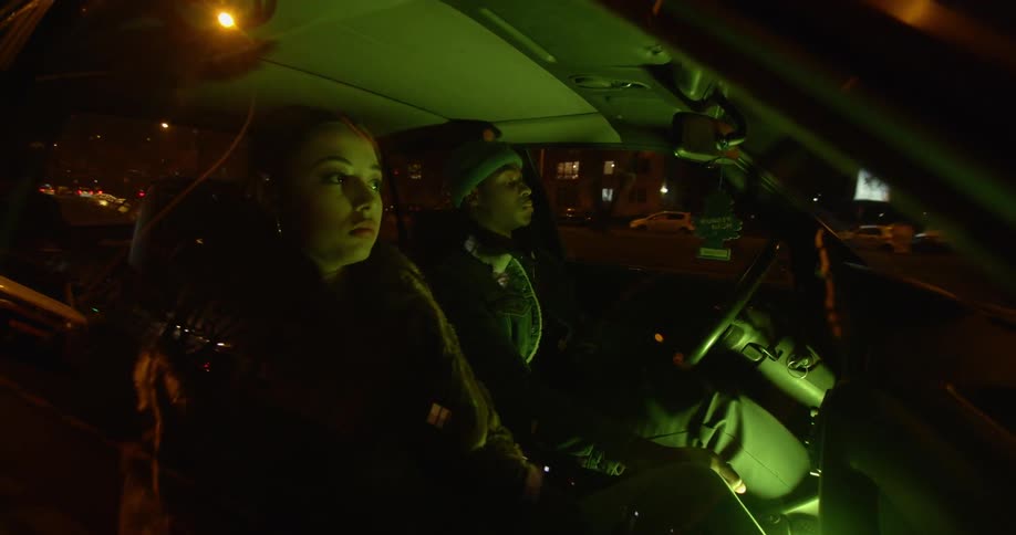 Couple driving car at night through city streets at night