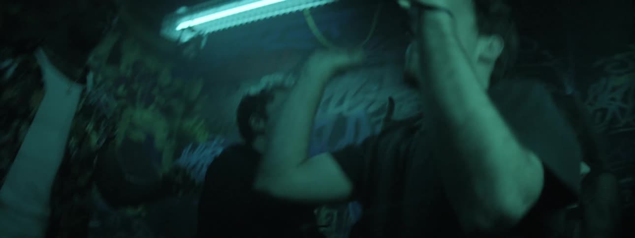 A large group of people dance wildly under strobing lights within a dance club