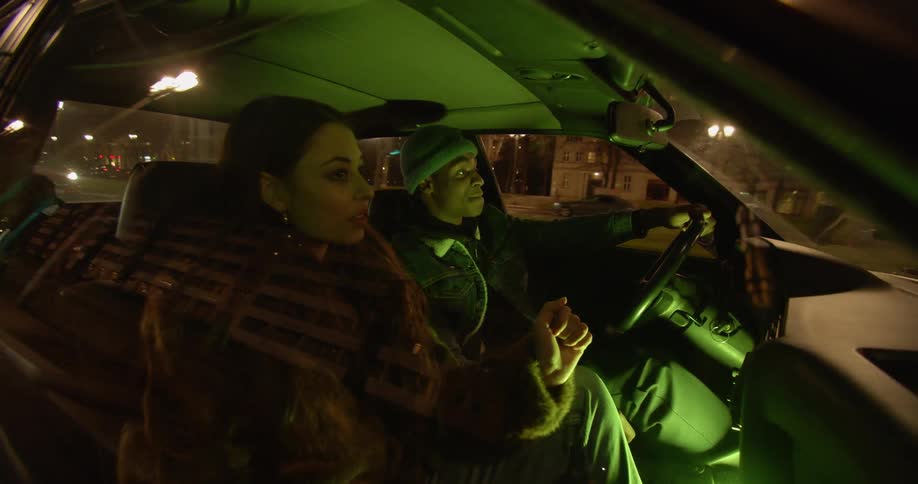 A man and woman sway and sing along with the music inside a car while driving