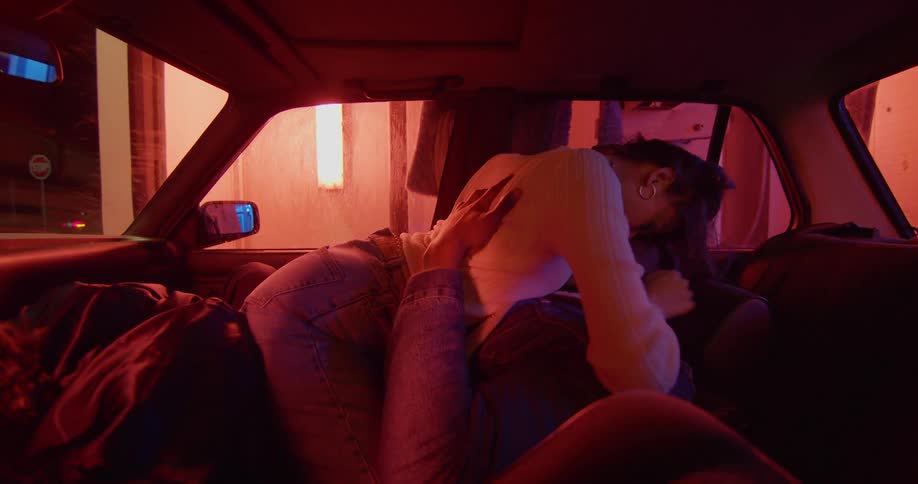 A couple making out in a car as it travels through a car wash