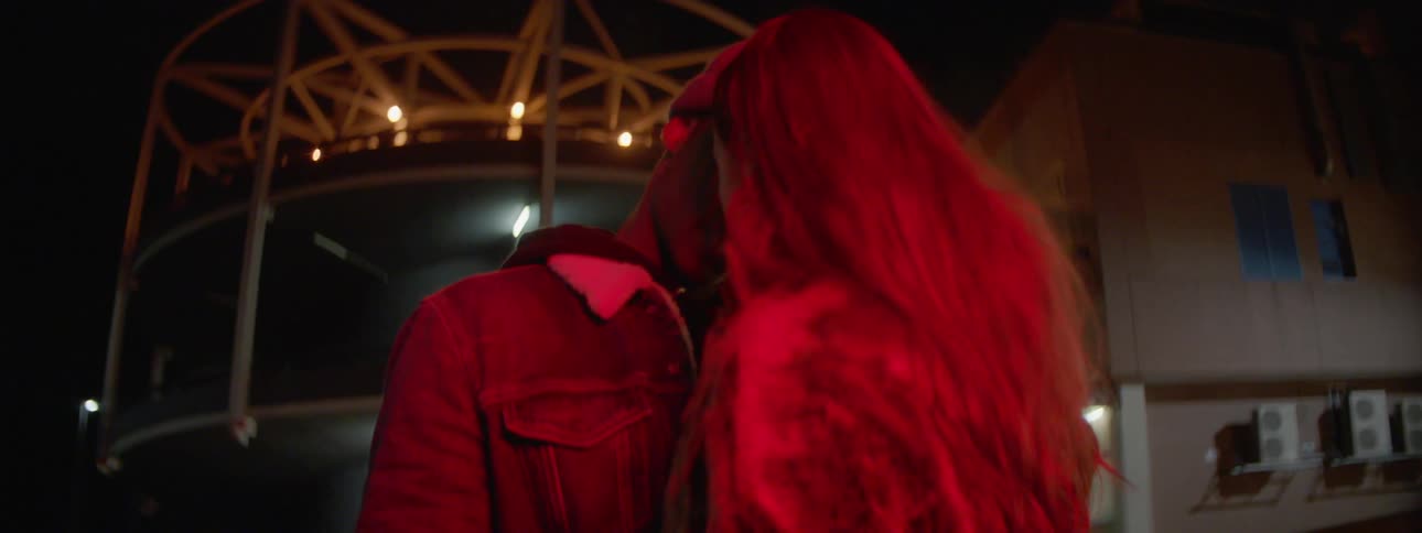 Black man and white woman kissing each other in the middle of the street at night