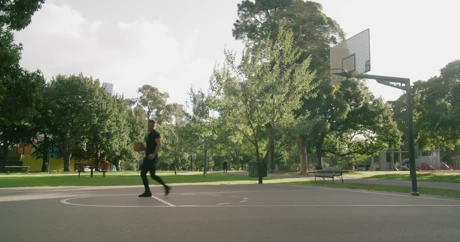 Man shooting hoops on basketball court in the park