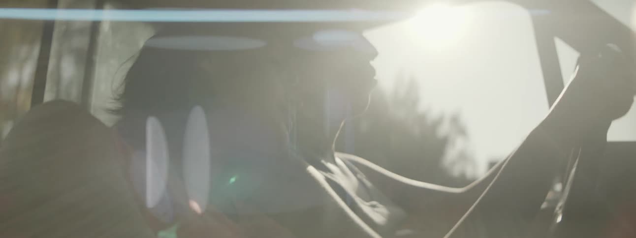 A woman leans her head on a mans shoulder as he drives
