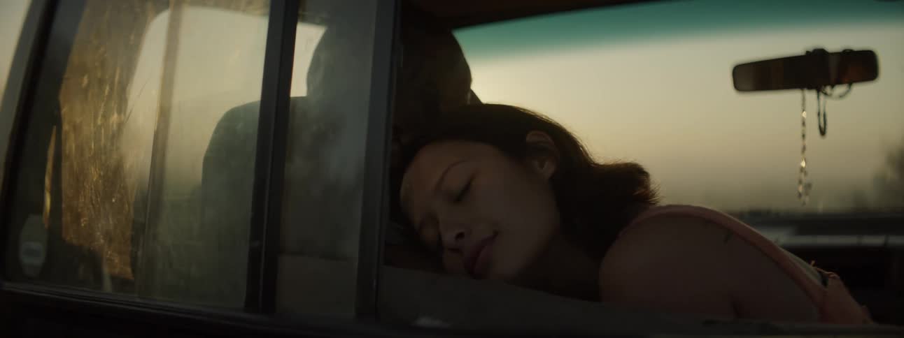 A woman sits in a vehicle and rests her head on a mans shoulder