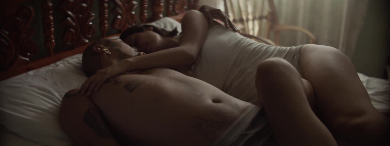 White woman and tattooed man hugging in the bed
