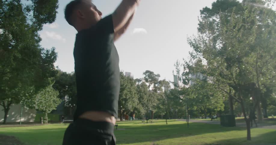 A man plays basketball at a court in a park surrounded by trees