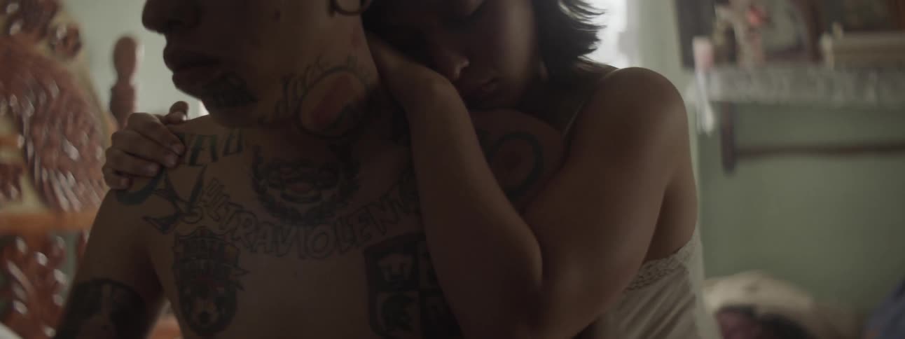 Woman gives man a back hug in bedroom