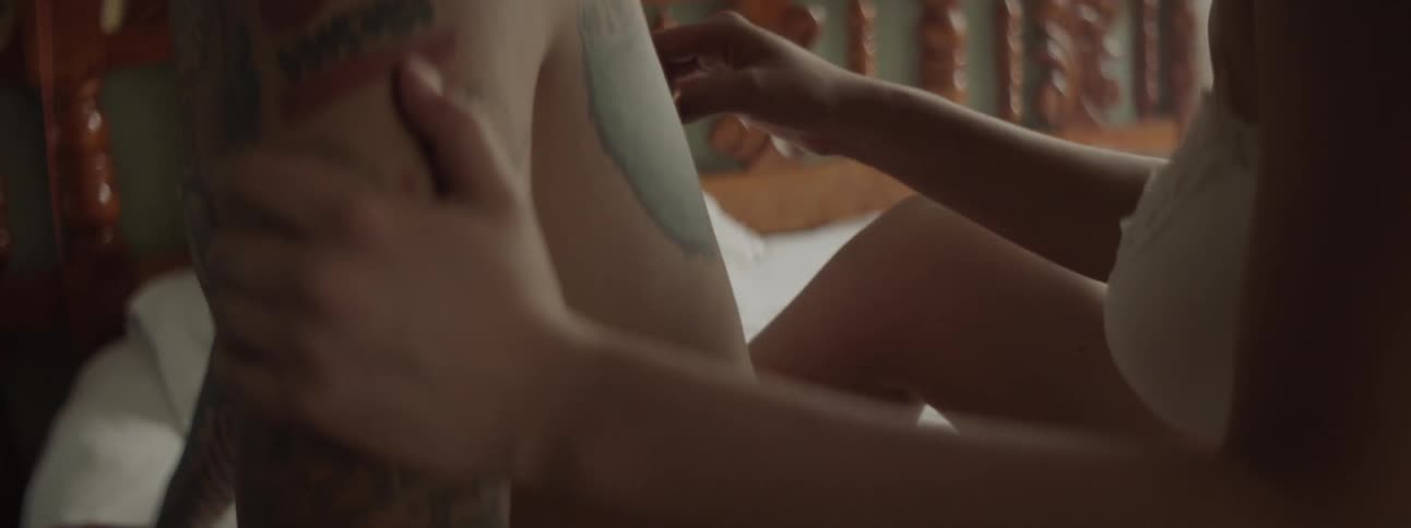 A woman traces her finger along a tattoo on the back of her male companion