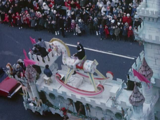 A man on a parade float waves at the crowd