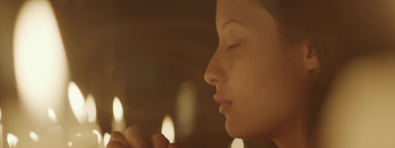 Woman prays among lit candles