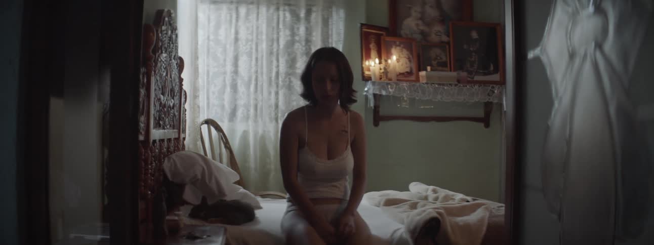 A young woman sitting on the edge of her bed