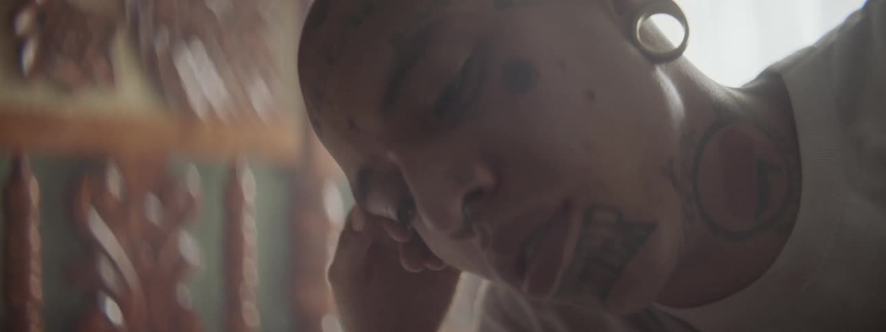A tattooed man stroking a womans bare stomach while resting on a bed