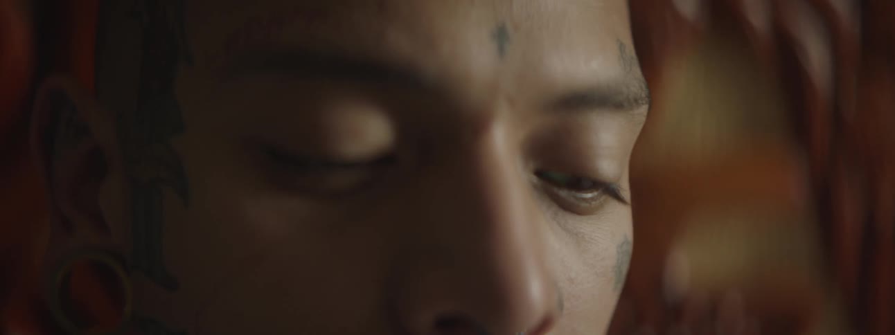 A man with gauge earrings and tattoos on his face