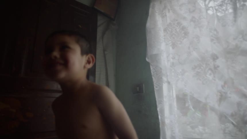 A boy laying on a bed as another boy jumps up and down on it