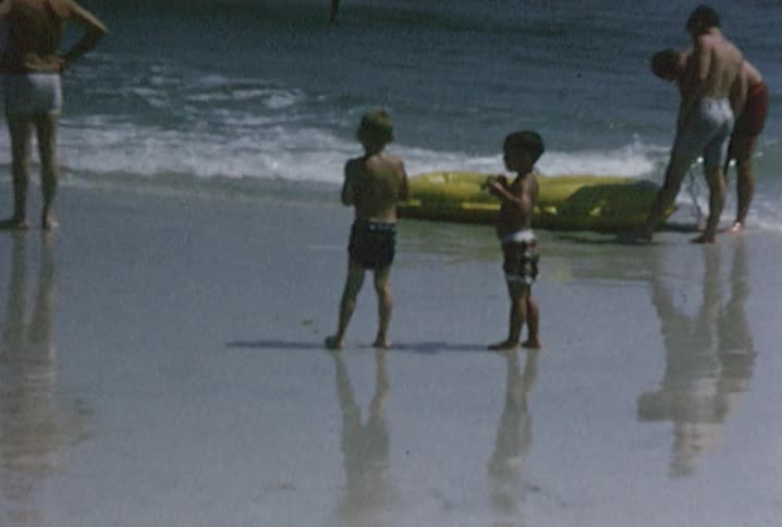 Men and boys in swimming trunks on the beach