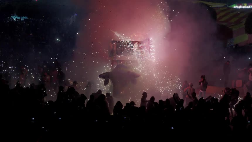 A crowd of people watch a concert with a light display