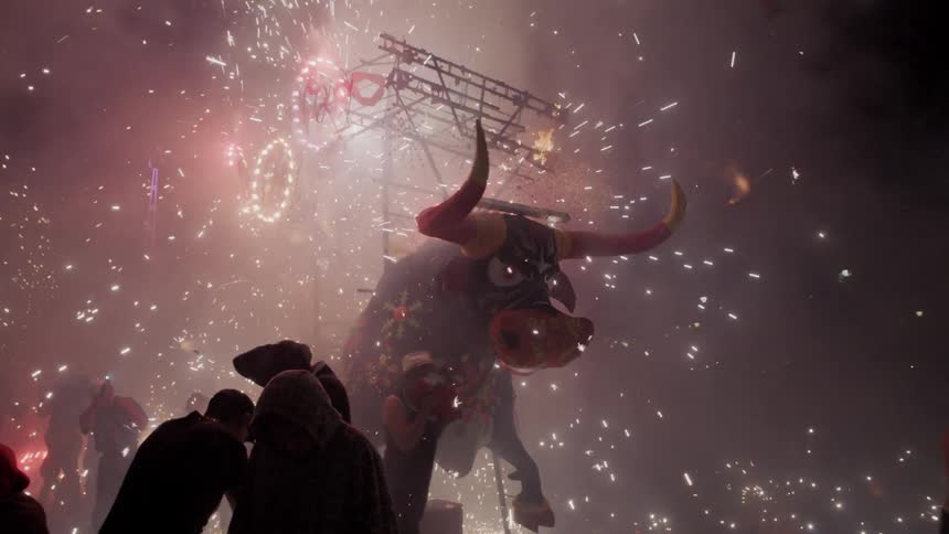 People run around as a large statue of a bull turns in a circle and sparks fly everywhere