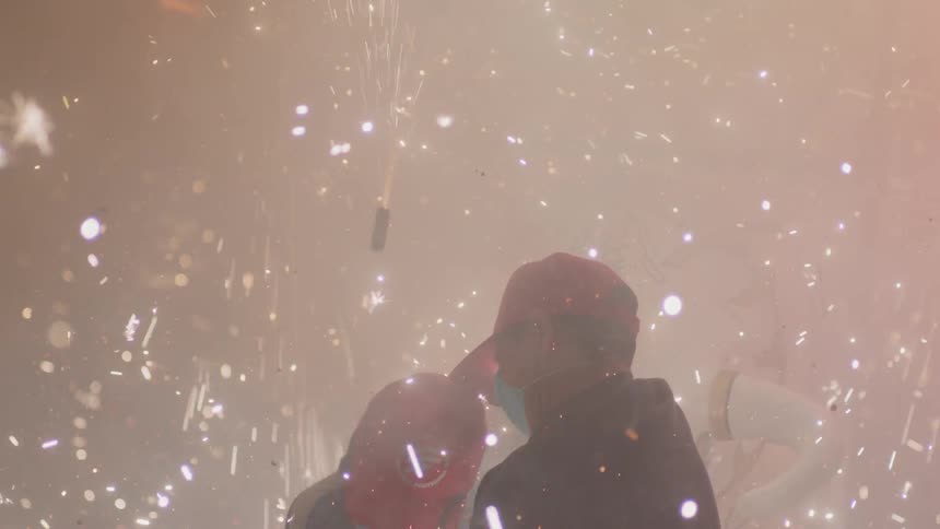 People with masks run through flying sparks and debris