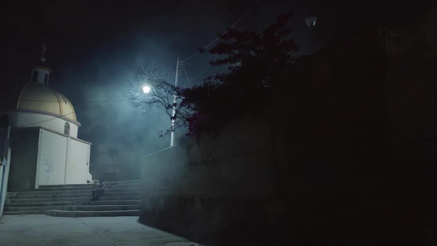 Musician sitting on steps under a streetlight at night