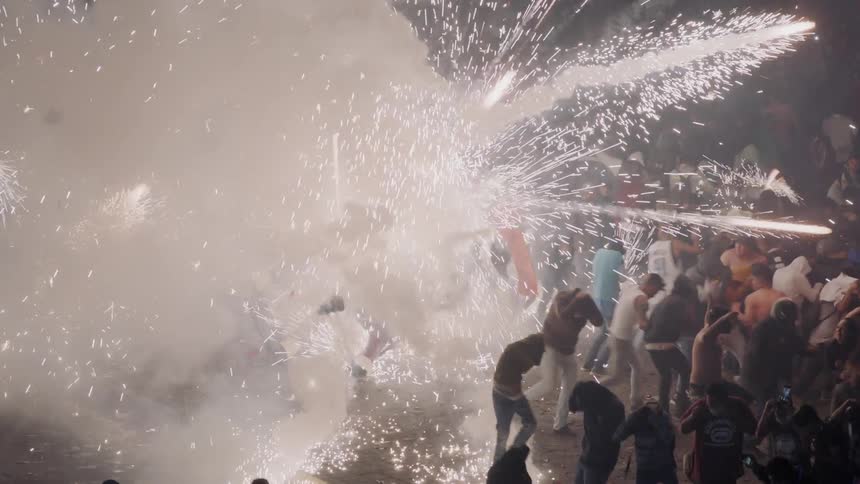 Fireworks suddenly exploding at ground level in a crowd on a celebration at night